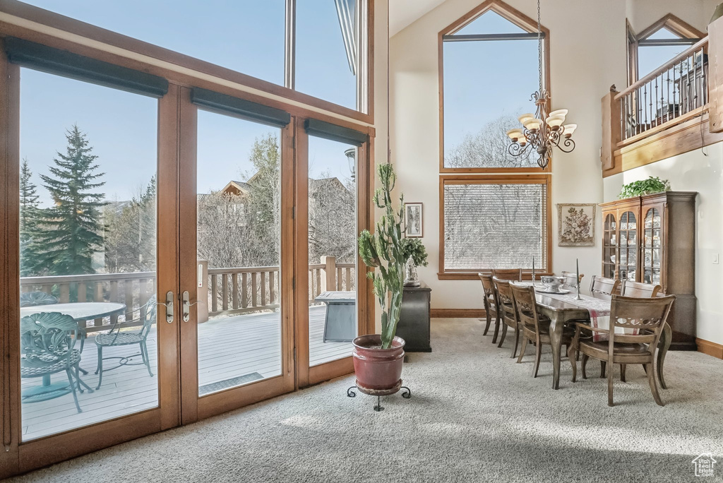 Doorway to outside with carpet, a chandelier, a towering ceiling, and baseboards