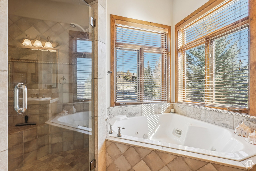 Full bath featuring healthy amount of natural light, a tub with jets, and a stall shower
