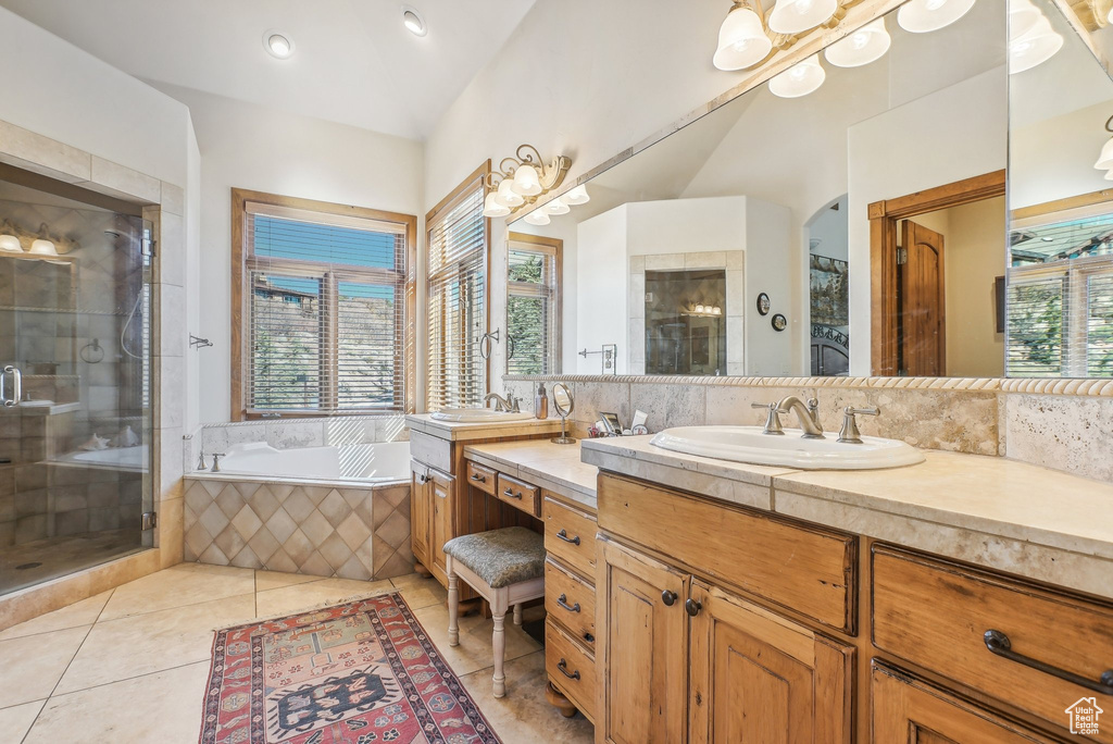 Full bath with vanity, a shower stall, a garden tub, tile patterned flooring, and vaulted ceiling