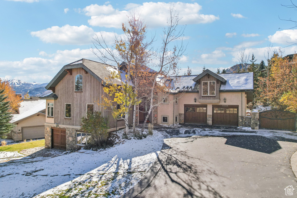 View of front of house featuring stone siding, an attached garage, asphalt driveway, and stucco siding