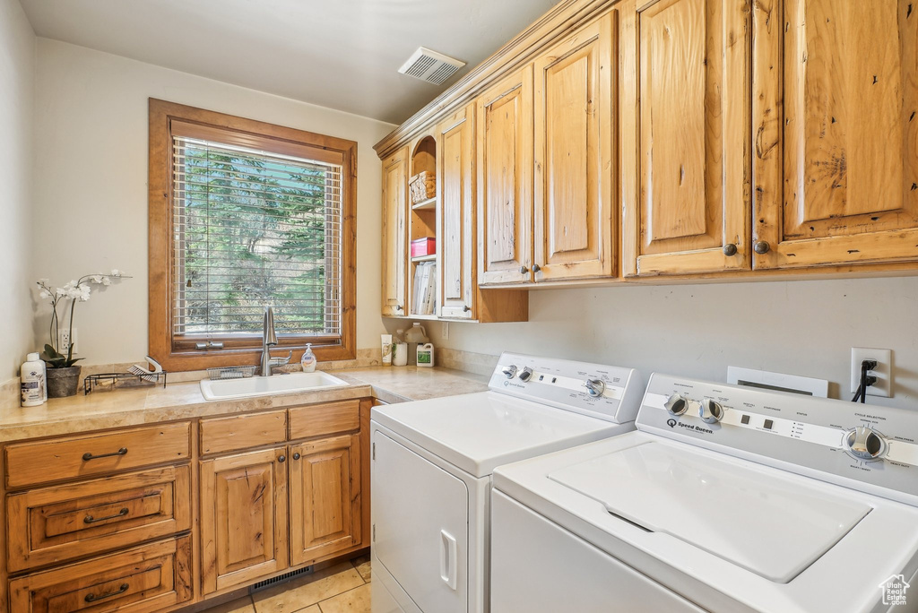 Laundry room featuring independent washer and dryer, cabinet space, and light tile patterned floors