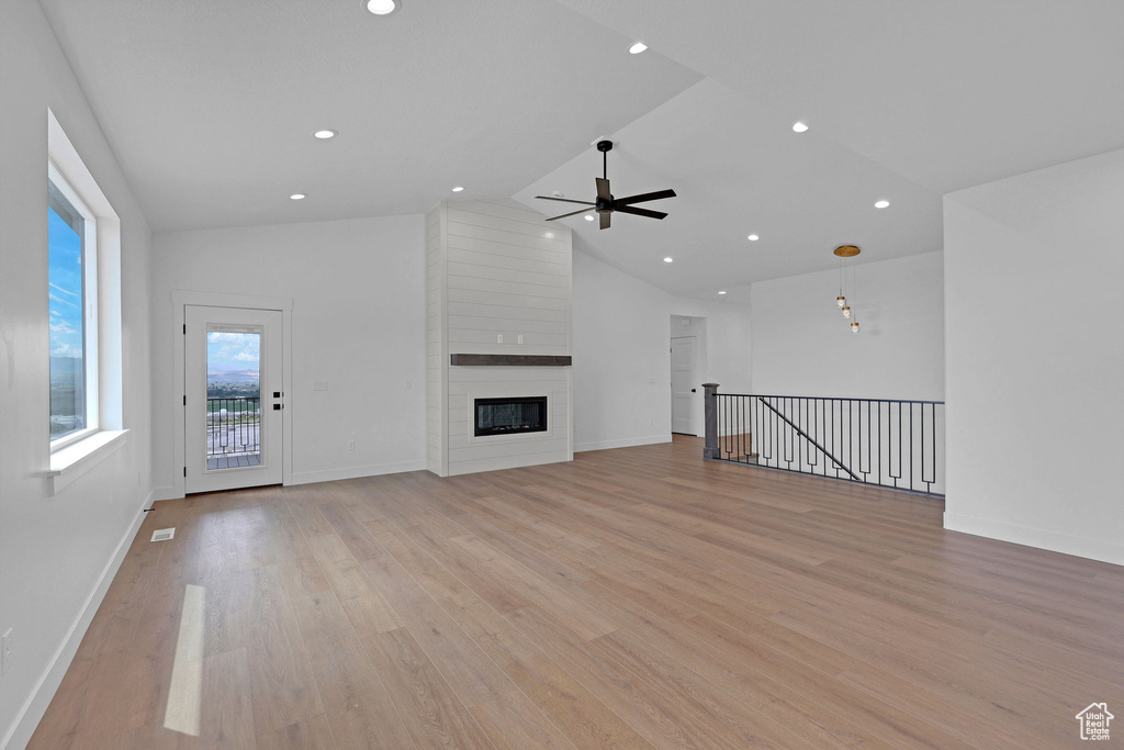 Unfurnished living room featuring a ceiling fan, light wood-type flooring, lofted ceiling, recessed lighting, and baseboards