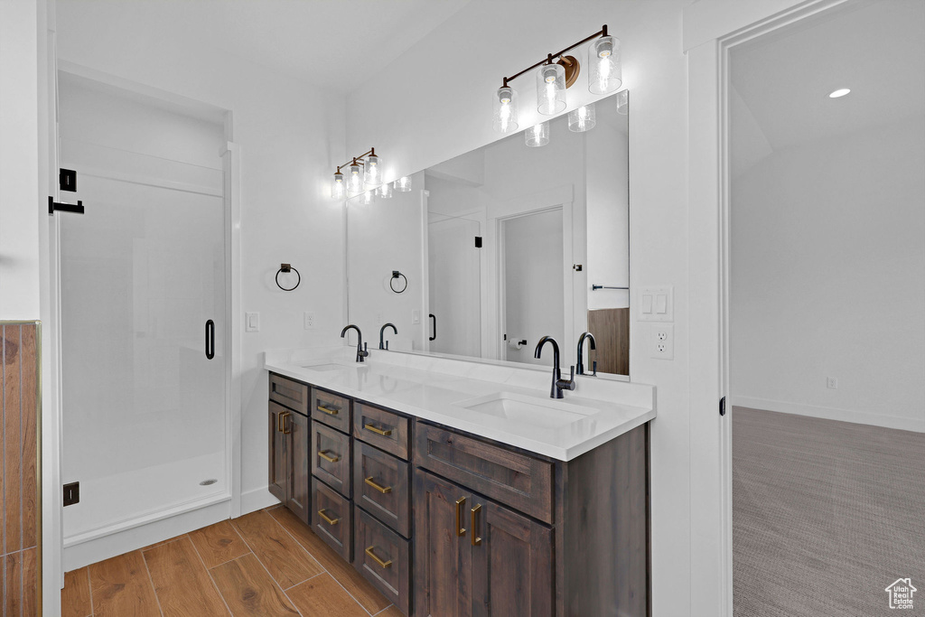 Full bathroom featuring double vanity, a shower stall, and wood finished floors