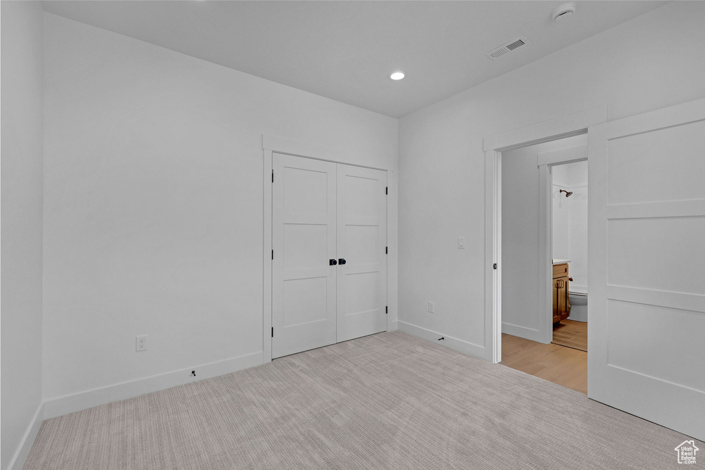 Unfurnished bedroom featuring light carpet, baseboards, recessed lighting, a closet, and ensuite bathroom