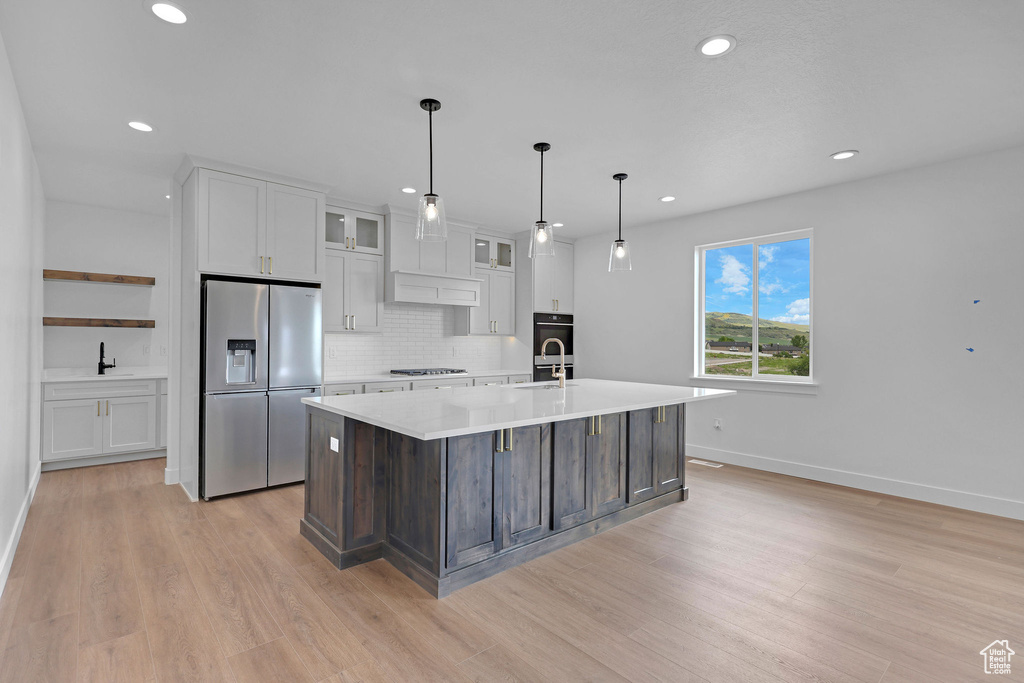 Kitchen with stainless steel fridge with ice dispenser, light countertops, white cabinets, light wood-style floors, and recessed lighting