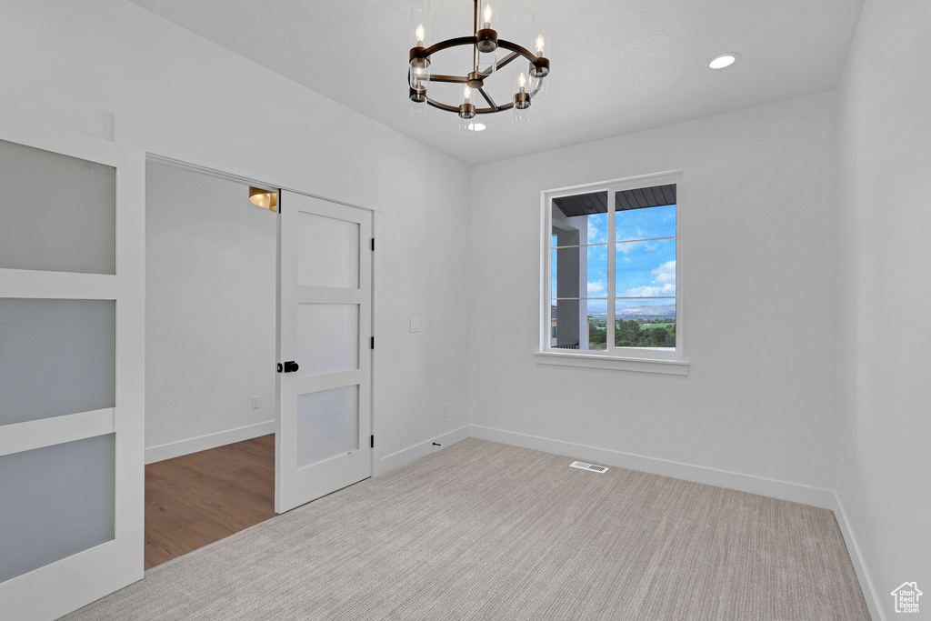 Carpeted empty room featuring a chandelier, baseboards, and recessed lighting