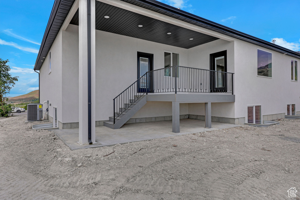 Back of house featuring stucco siding, central air condition unit, and a patio area