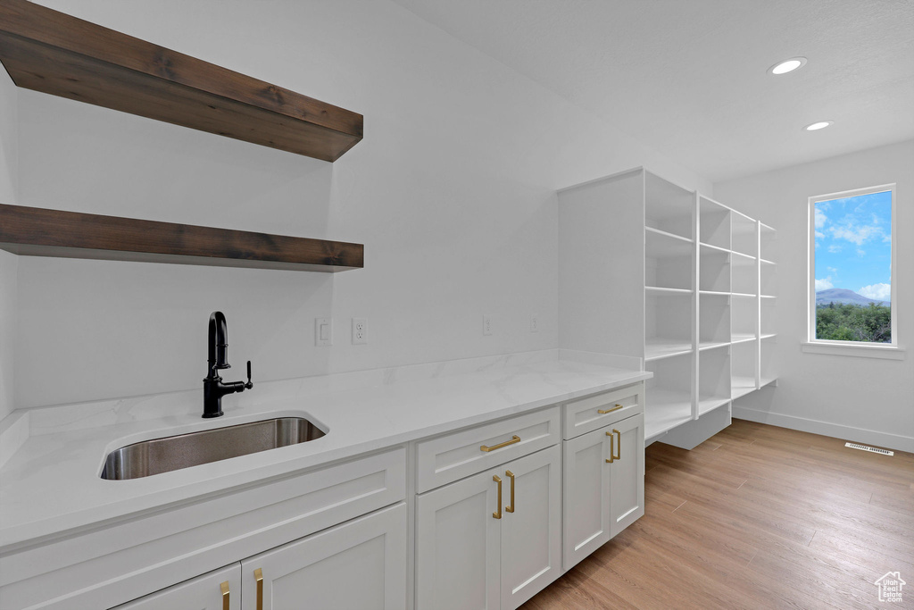 Bar area with a sink, baseboards, light wood-type flooring, and recessed lighting