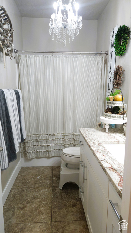 Full bath with vanity, shower / tub combo with curtain, toilet, and a chandelier