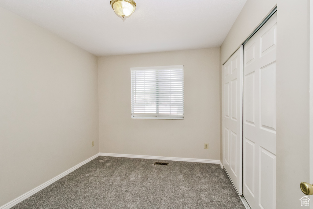 Unfurnished bedroom featuring carpet flooring, baseboards, and a closet