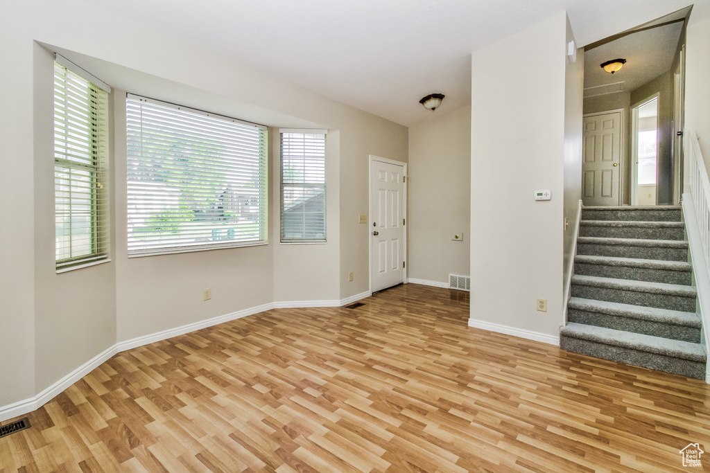 Unfurnished living room featuring light wood-style flooring, healthy amount of natural light, and baseboards