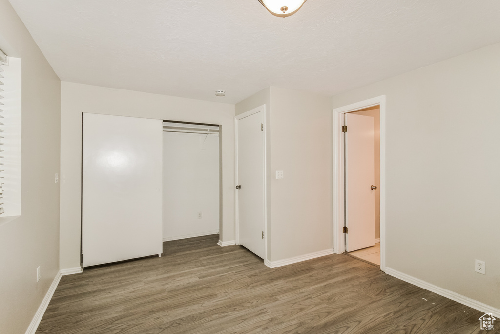 Unfurnished bedroom with wood finished floors, baseboards, and a closet