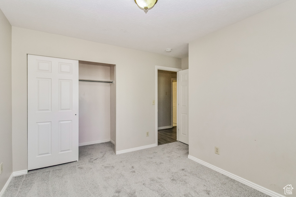 Unfurnished bedroom featuring carpet flooring, baseboards, and a closet