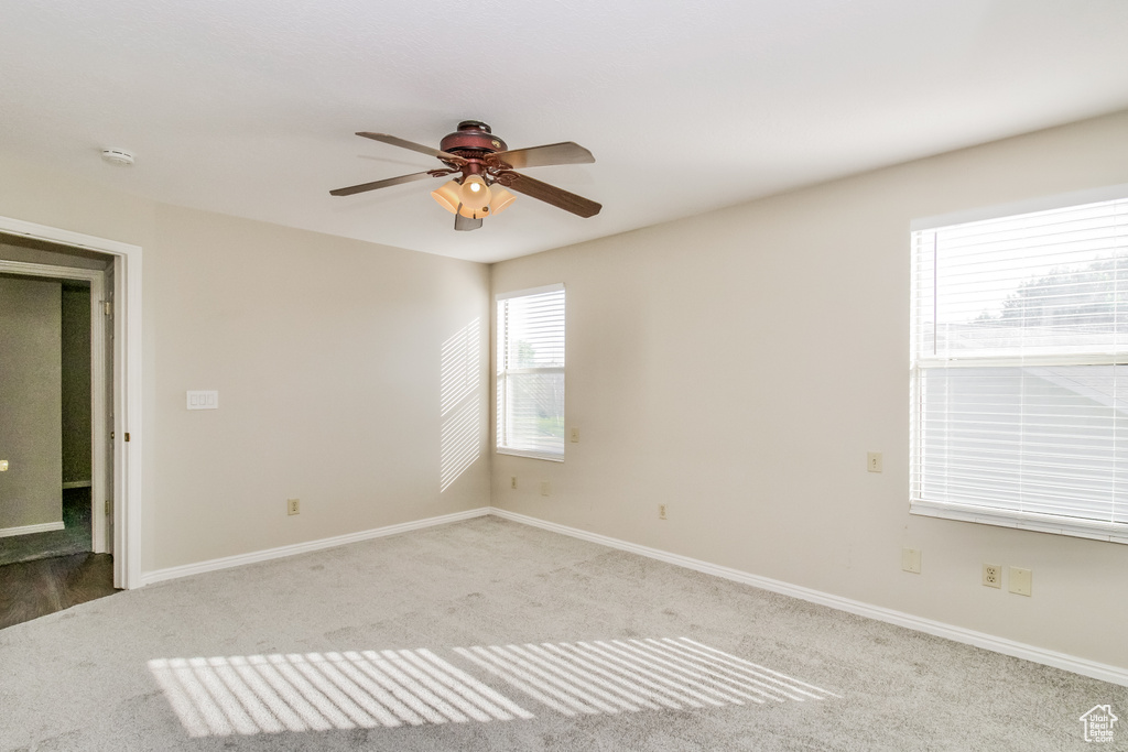 Unfurnished room featuring light carpet, a ceiling fan, and baseboards