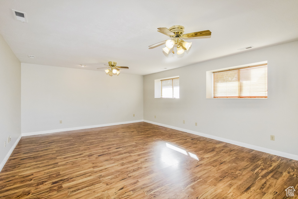 Spare room with a ceiling fan, wood finished floors, and baseboards