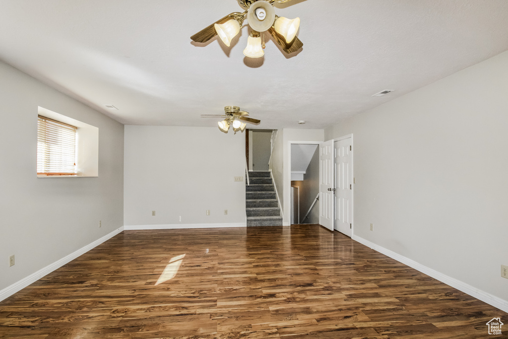 Spare room featuring ceiling fan, stairs, wood finished floors, and baseboards
