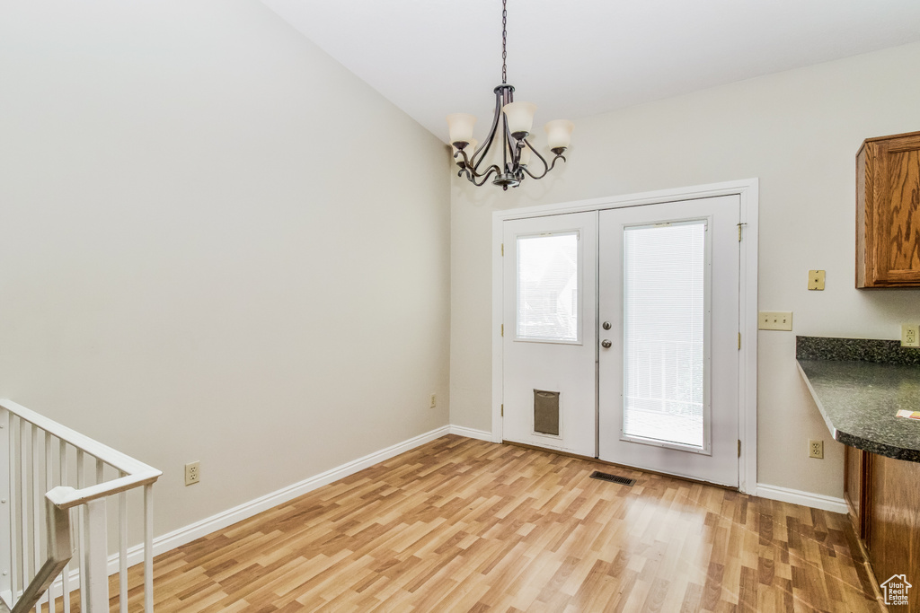 Foyer entrance with light wood-style floors, a chandelier, and baseboards