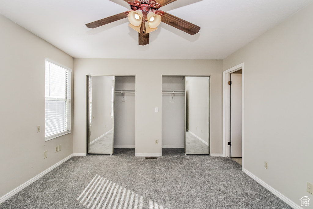 Unfurnished bedroom with multiple closets, carpet, baseboards, and a ceiling fan