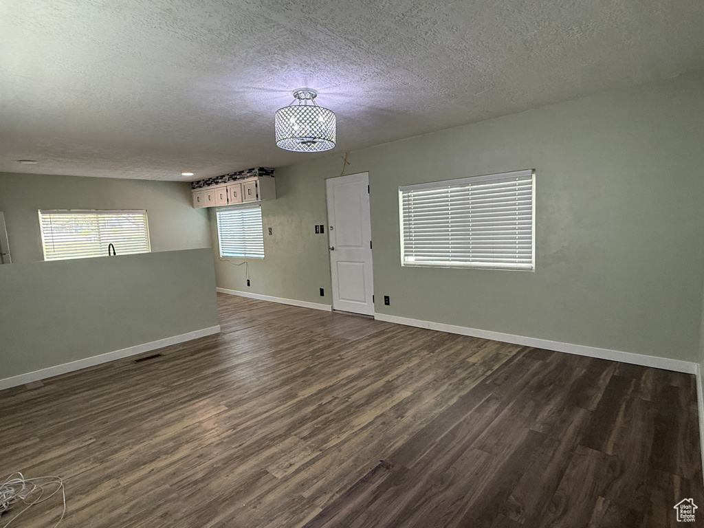 Spare room featuring a textured ceiling, dark wood-style flooring, and baseboards