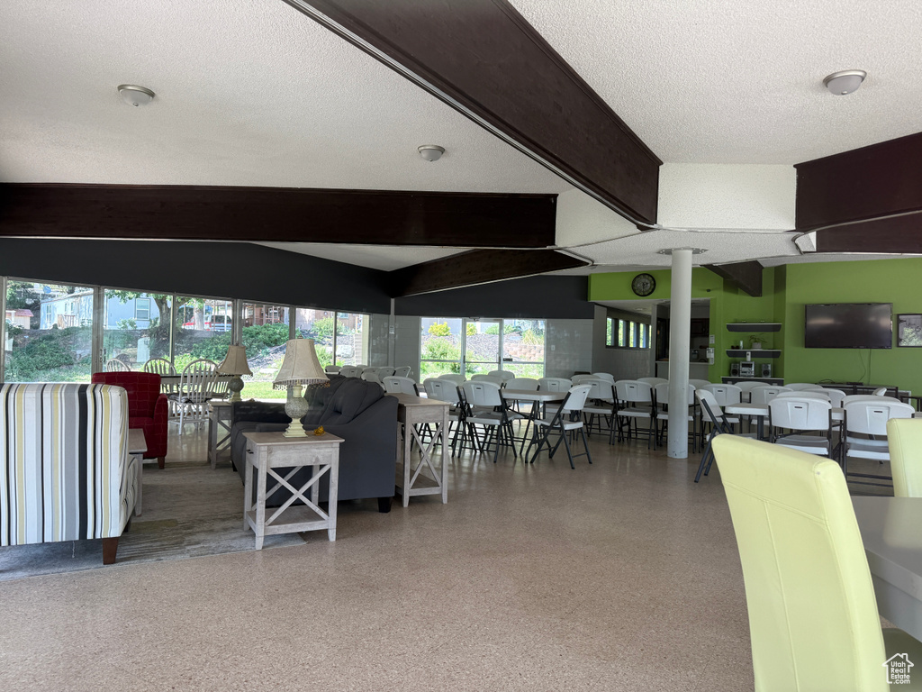 Living room with beamed ceiling, speckle patterned floor, and a textured ceiling