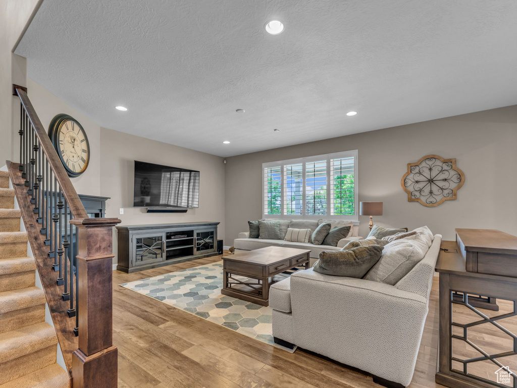 Living room with stairway, wood finished floors, recessed lighting, and a textured ceiling