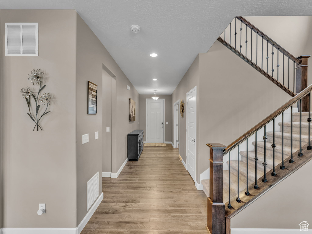 Hallway featuring recessed lighting, baseboards, light wood-style floors, and stairs