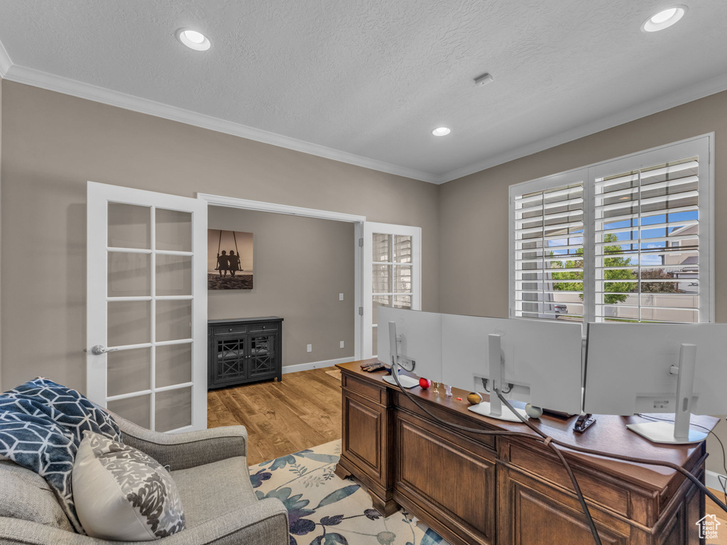 Office area featuring crown molding, light wood-type flooring, a textured ceiling, recessed lighting, and baseboards