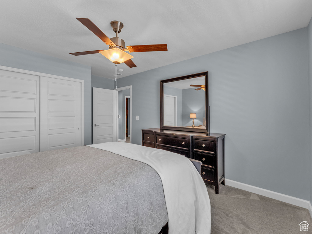 Carpeted bedroom with a closet, baseboards, and a ceiling fan