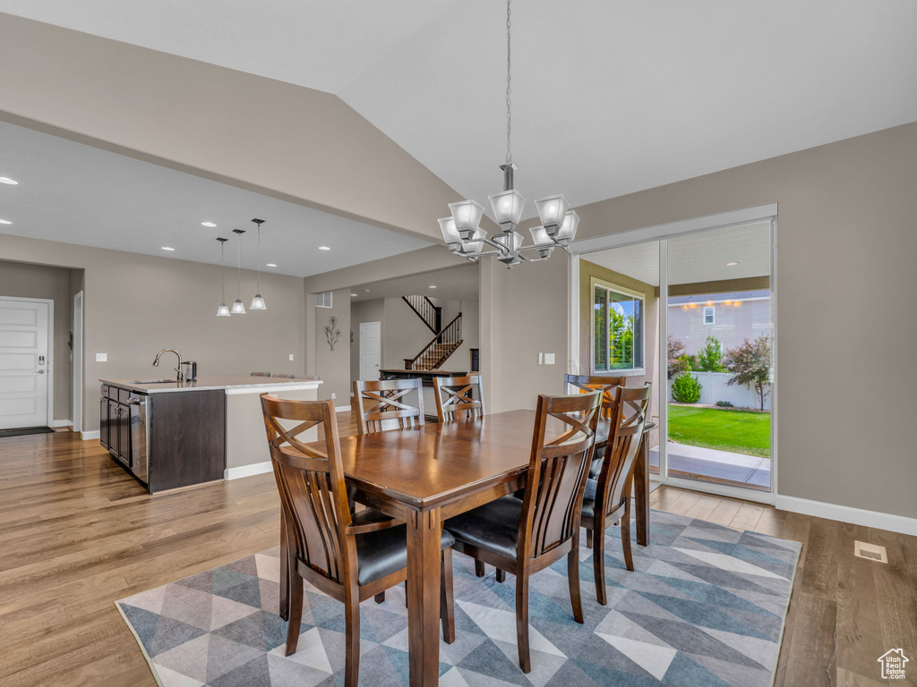 Dining room featuring stairs, wood finished floors, a chandelier, lofted ceiling, and recessed lighting