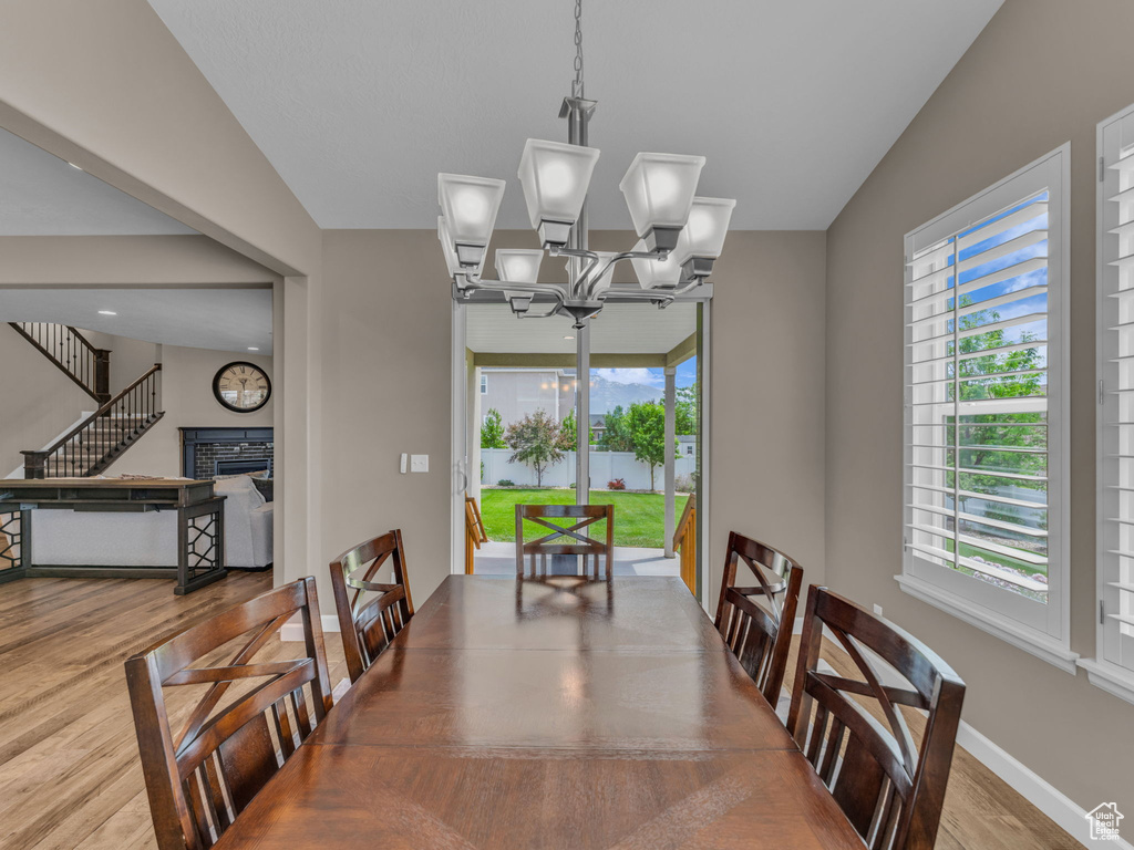 Dining room featuring wood finished floors, a chandelier, a fireplace, baseboards, and stairway