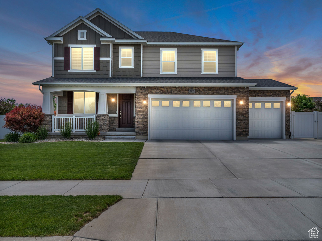 Craftsman inspired home featuring covered porch, concrete driveway, a garage, board and batten siding, and stone siding