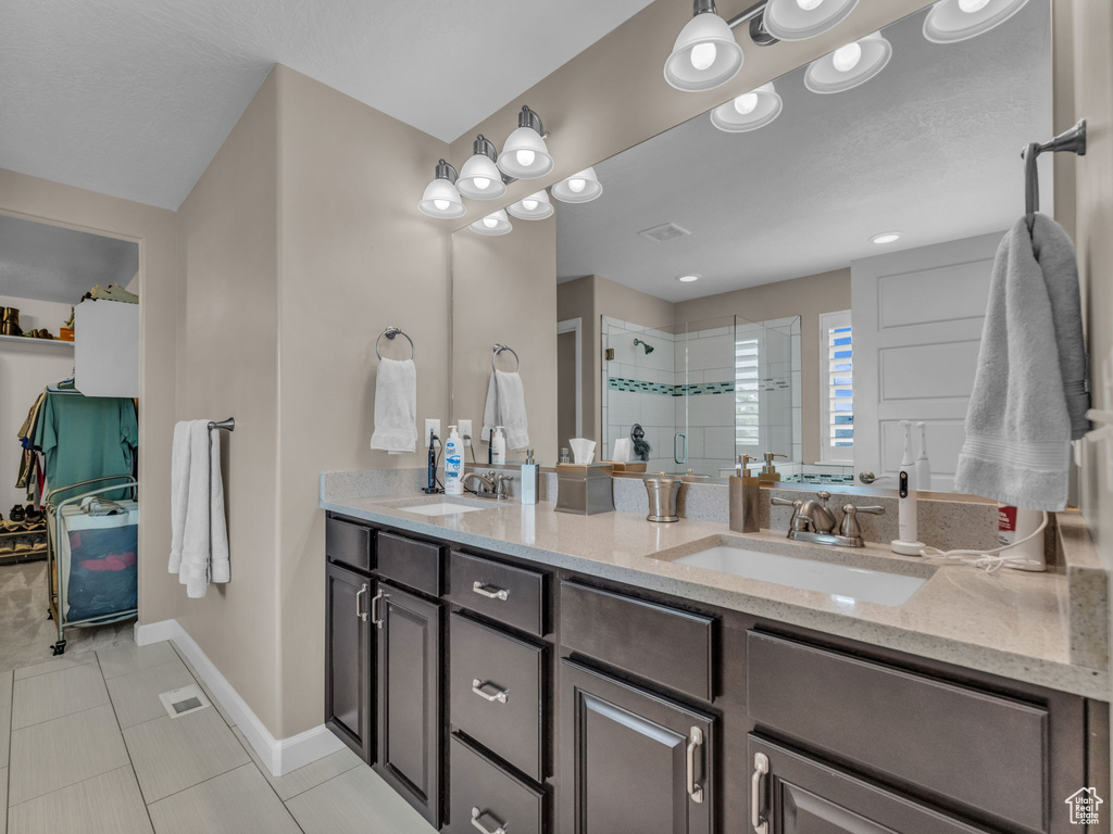 Full bathroom with a shower stall, double vanity, baseboards, and tile patterned flooring