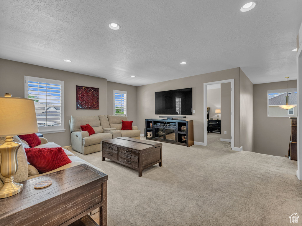 Living room with a textured ceiling, recessed lighting, light colored carpet, and baseboards