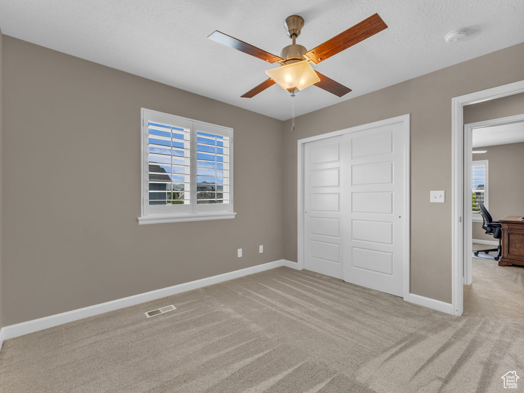 Unfurnished bedroom with carpet, a closet, baseboards, and a ceiling fan