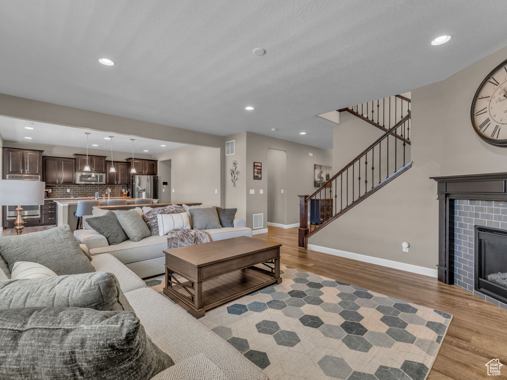 Living area featuring light wood-style floors, baseboards, recessed lighting, stairs, and a glass covered fireplace