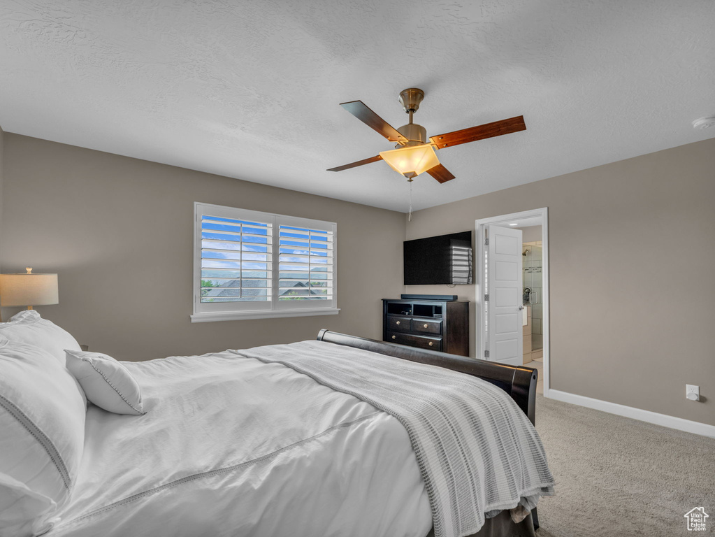 Carpeted bedroom featuring baseboards, ceiling fan, and a textured ceiling