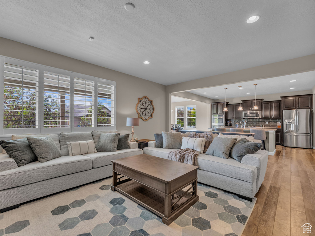 Living area with light wood-type flooring and recessed lighting