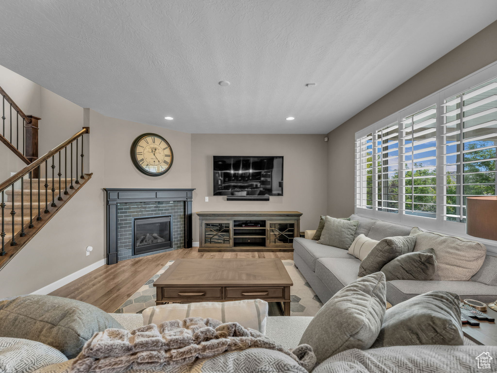 Living area with wood finished floors, recessed lighting, stairway, a tiled fireplace, and baseboards