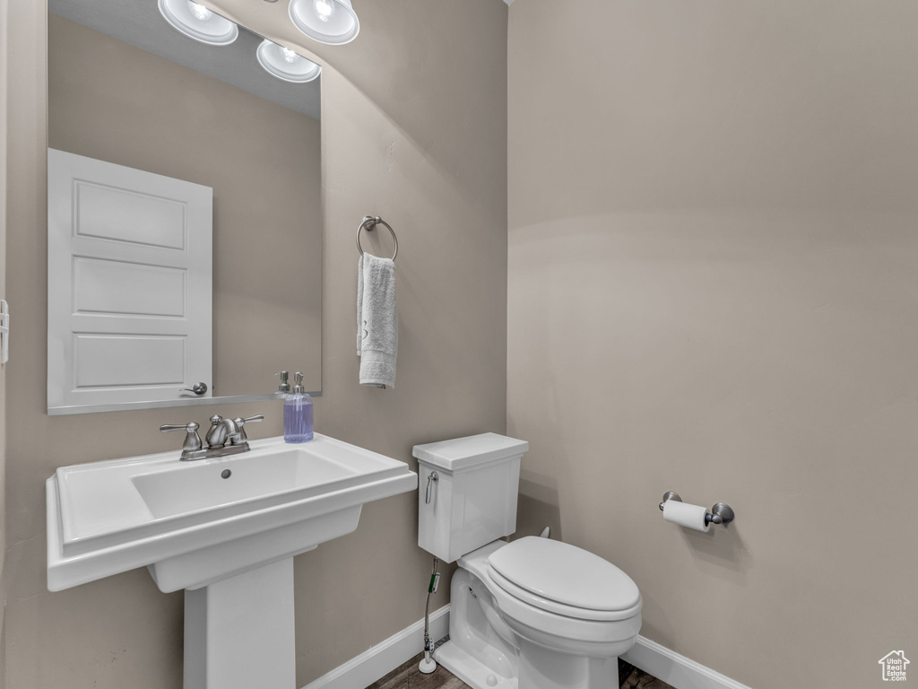 Half bath with toilet, baseboards, and a sink