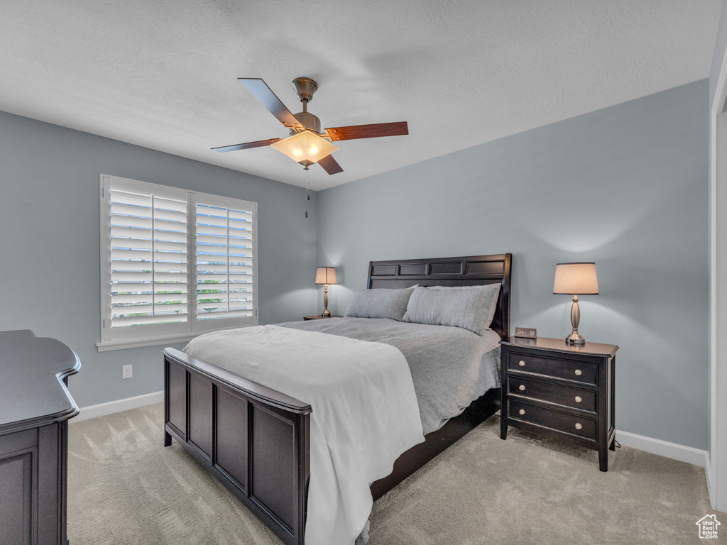 Bedroom featuring light colored carpet, baseboards, and a ceiling fan