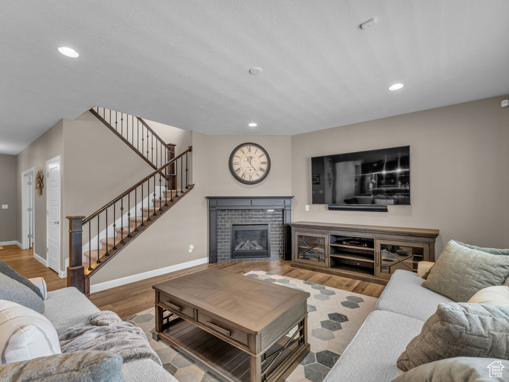 Living room featuring baseboards, stairway, recessed lighting, wood finished floors, and a tiled fireplace