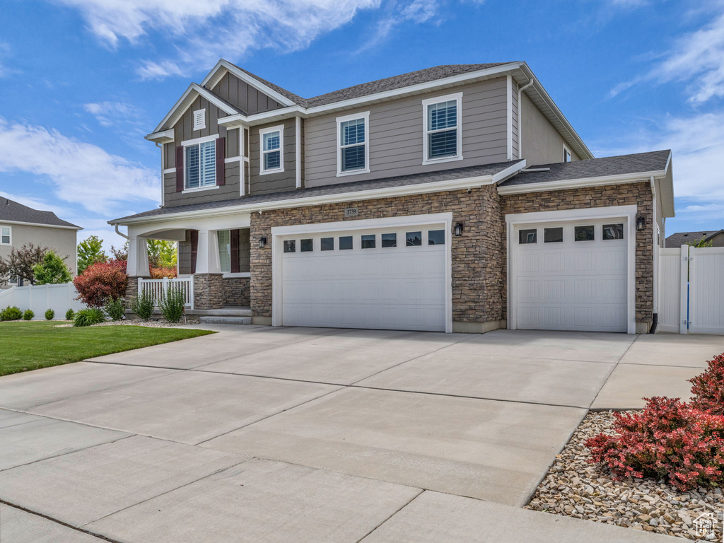 Craftsman inspired home with a porch, concrete driveway, an attached garage, and stone siding