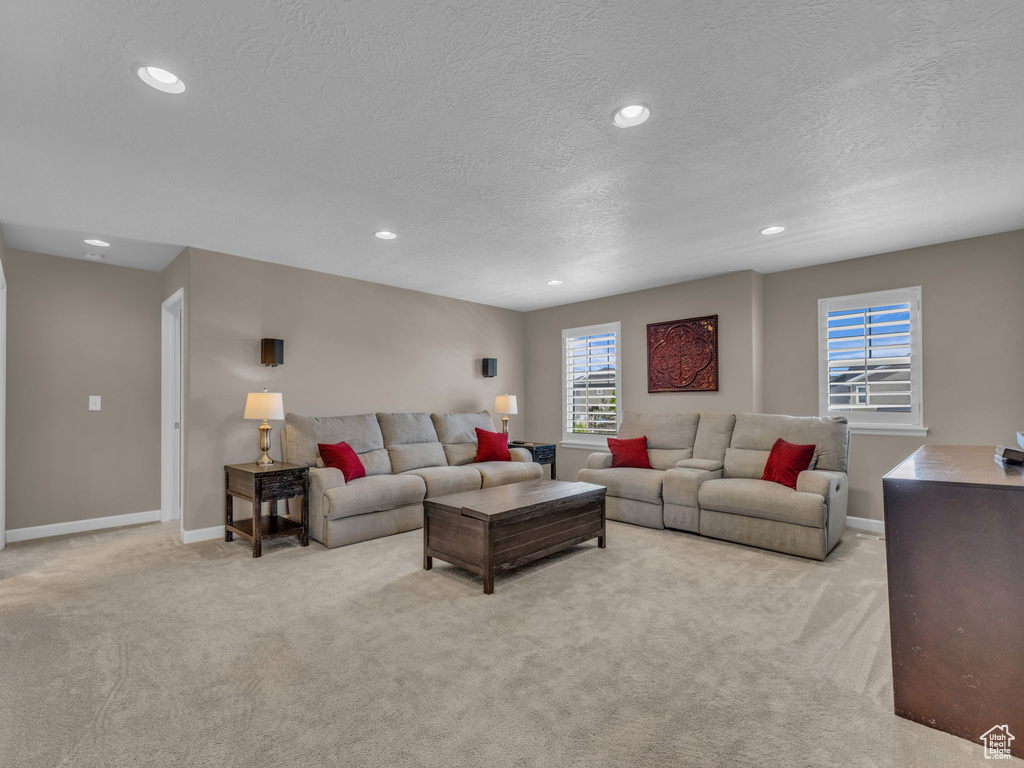 Carpeted living room with a textured ceiling, recessed lighting, and baseboards