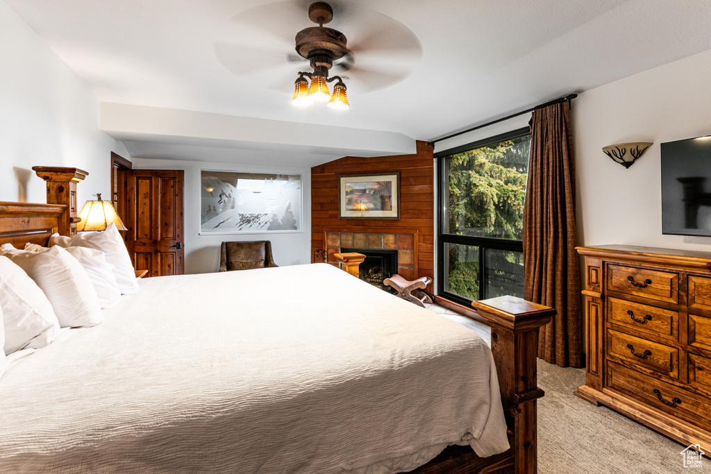 Carpeted bedroom featuring lofted ceiling, a fireplace, and ceiling fan