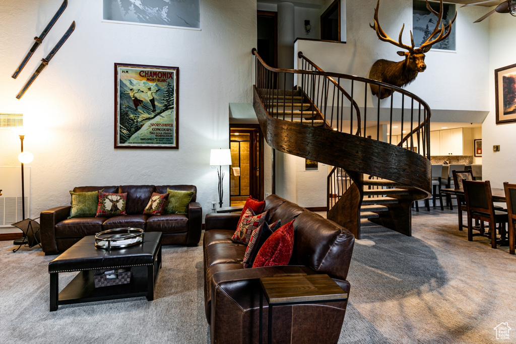 Living room with carpet, stairs, and a towering ceiling