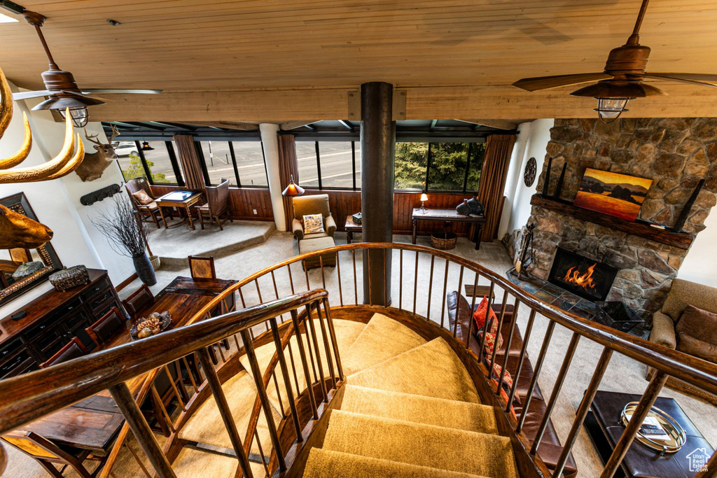 Staircase featuring a ceiling fan, wooden ceiling, carpet flooring, and a fireplace