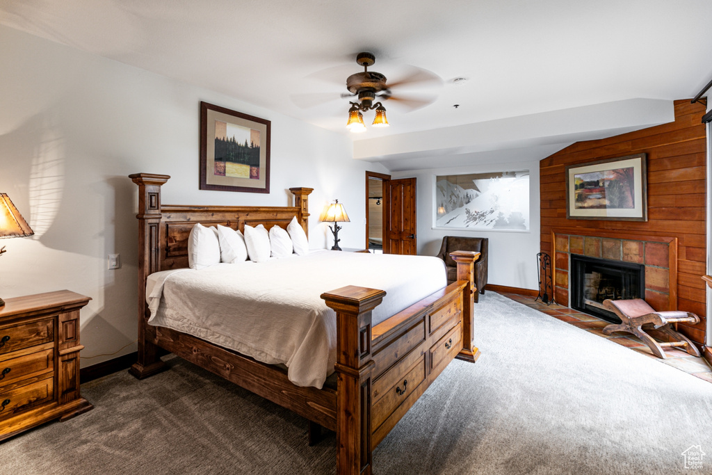Bedroom with dark colored carpet, baseboards, a tiled fireplace, and a ceiling fan