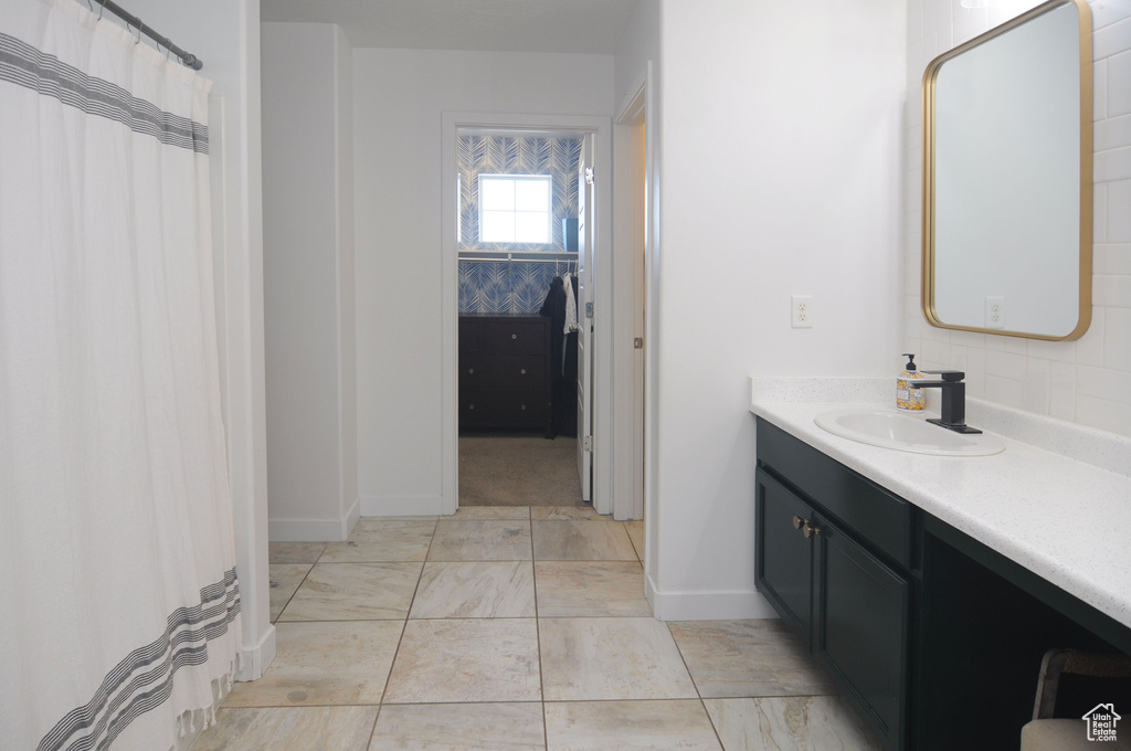 Full bath featuring vanity, baseboards, and marble look tiles