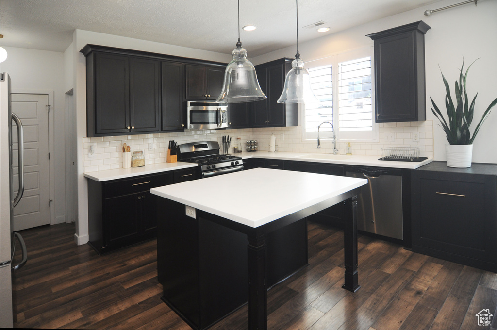 Kitchen featuring appliances with stainless steel finishes, a sink, dark wood-style floors, tasteful backsplash, and recessed lighting