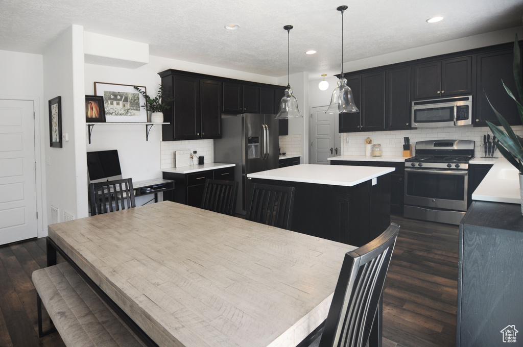 Kitchen with appliances with stainless steel finishes, dark cabinets, dark wood-style flooring, a center island, and recessed lighting